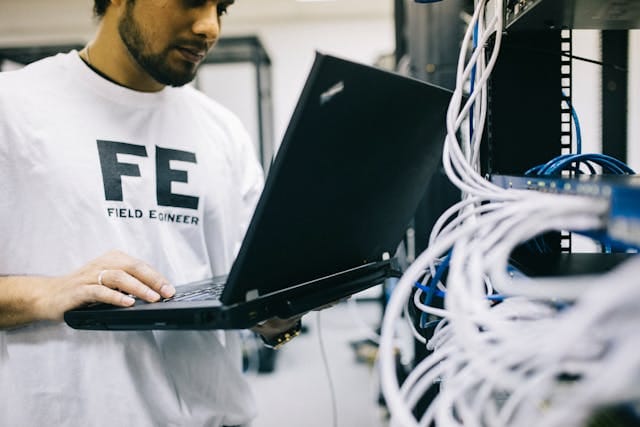 Netwerkbeheerder met zijn laptop bij een patchkast